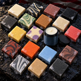 Overhead view of all eighteen Full Salute soap bars with an open jar of Balm of the Brave on wet slate