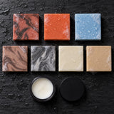 Overhead view of the Ultimate Tallow soap bars with an open jar of Balm of the Brave on wet slate