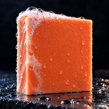 Close up of the Orange Man Grit soap bar with fresh lather on wet slate