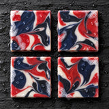 Overhead view of four 250 Proof red white and blue marbled soap bars on wet slate